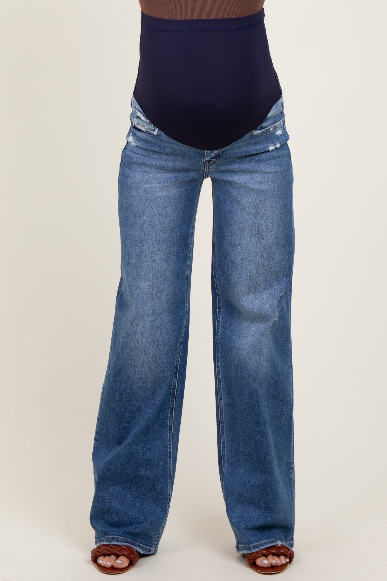 maternity wear dark blue high-waisted jeans with distressed details, worn by a model with a visible baby bump