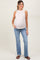 woman wearing a light pink sleeveless maternity top with a baby bump and paired with light blue flared jeans