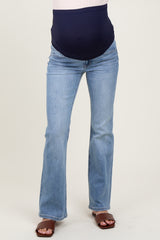 woman wearing a pair of light blue maternity flared jeans with a navy blue over-the-bump waistband