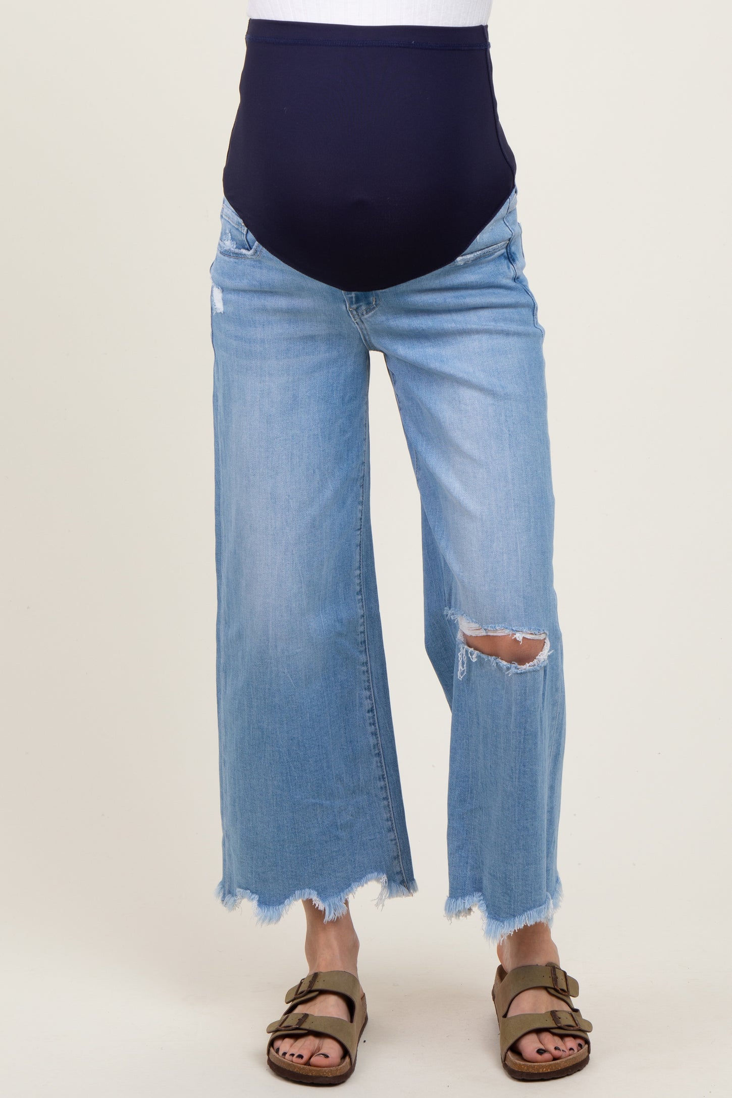 woman wearing a pair of light blue distressed maternity jeans with a navy blue over-the-bump waistband