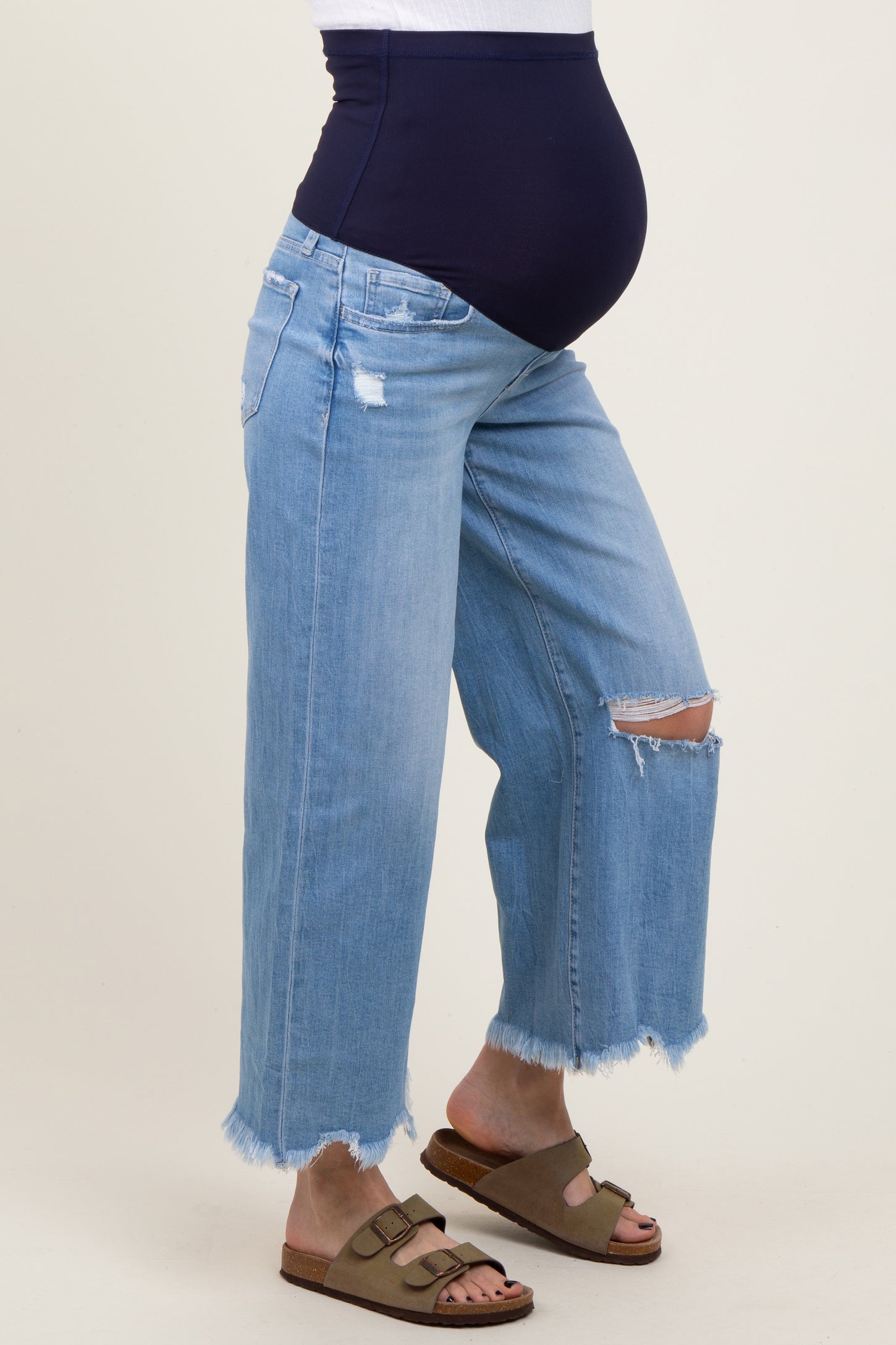 maternity wear blue distressed wide-leg jeans with a navy belly panel and a visible baby bump