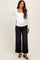 woman wearing a white long sleeve maternity top and black wide leg jeans with a visible baby bump