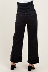 woman wearing black wide-leg maternity jeans with a fold-over waistband, showing a relaxed fit from the back