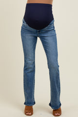 woman wearing blue maternity jeans with a dark waistband and standing in brown heeled sandals