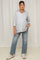 woman wearing a light blue maternity button-up shirt and distressed jeans, with a visible baby bump