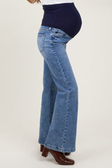 woman wearing a navy blue maternity belly band with flared light blue maternity jeans and a visible baby bump