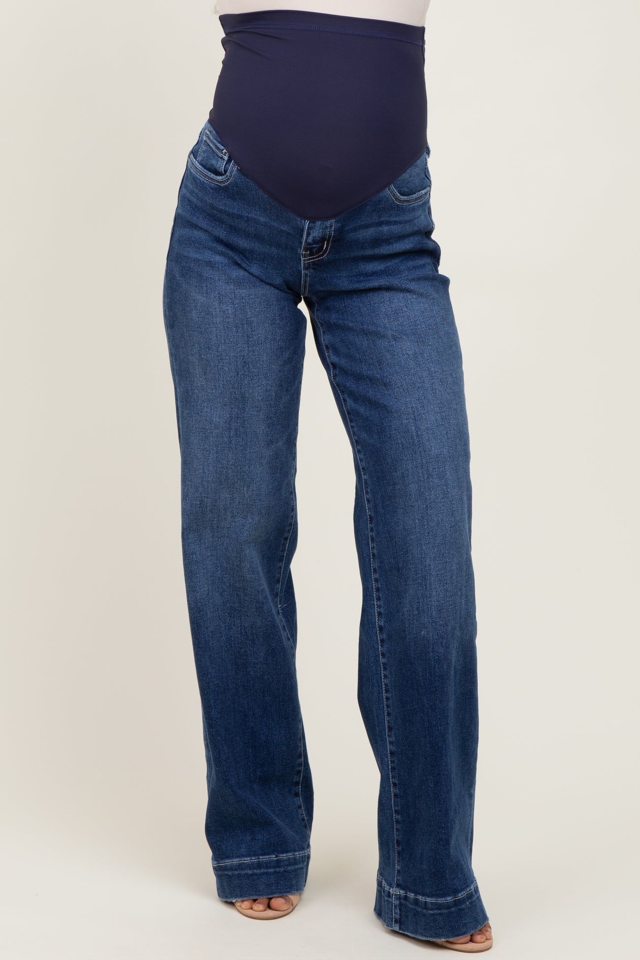 woman wearing dark blue maternity jeans with a fitted belly panel and a flared leg style