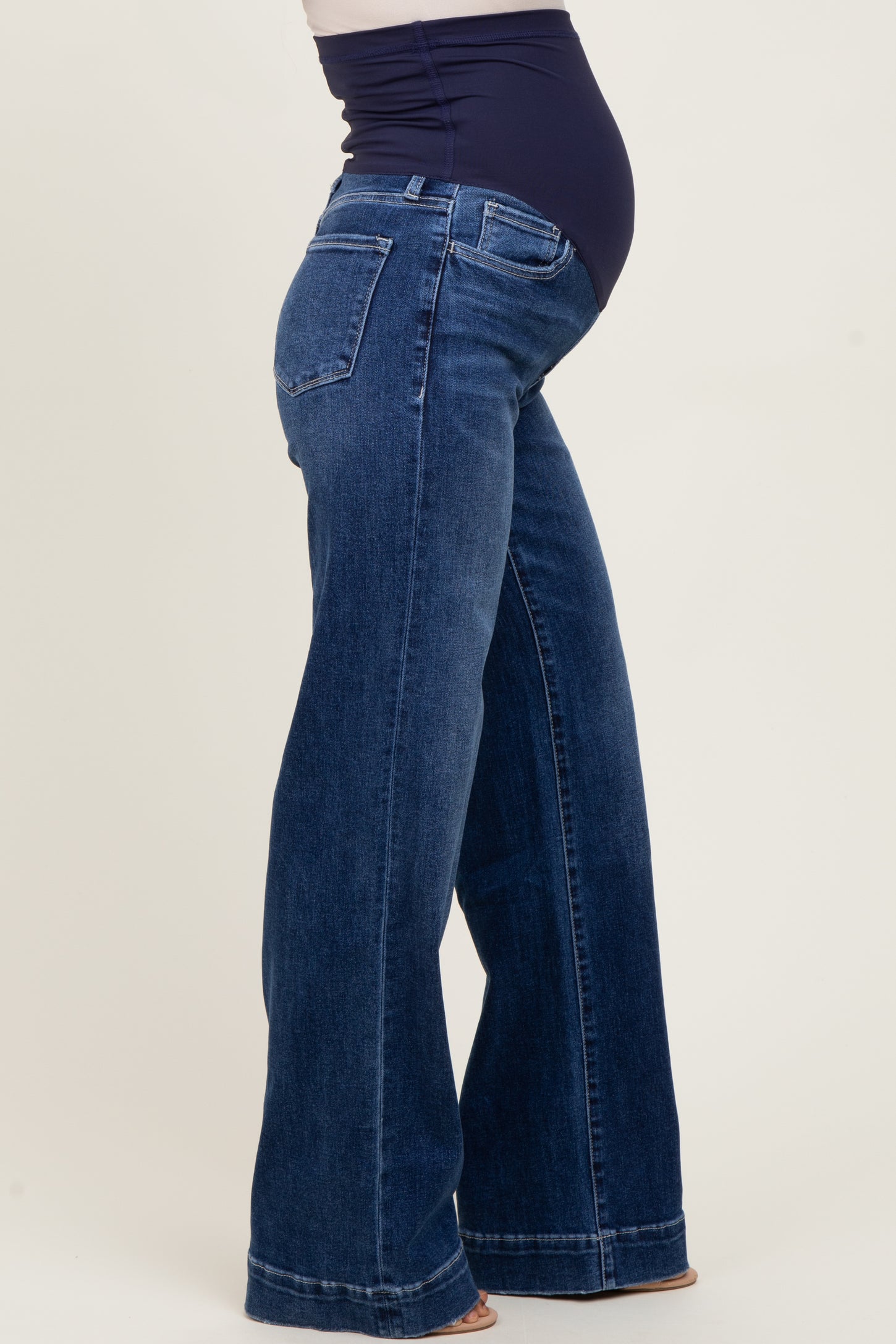maternity wear in dark wash flared jeans with a supportive over-the-bump band and a visible baby bump