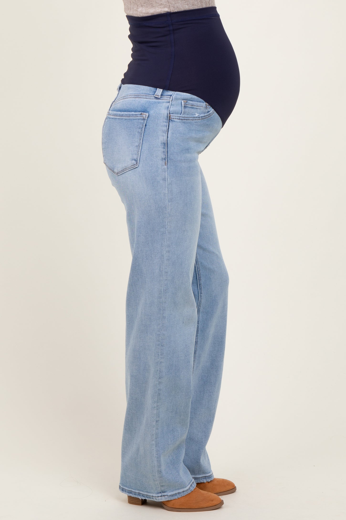 woman wearing light blue maternity jeans with a dark blue over-the-bump panel, highlighting her baby bump