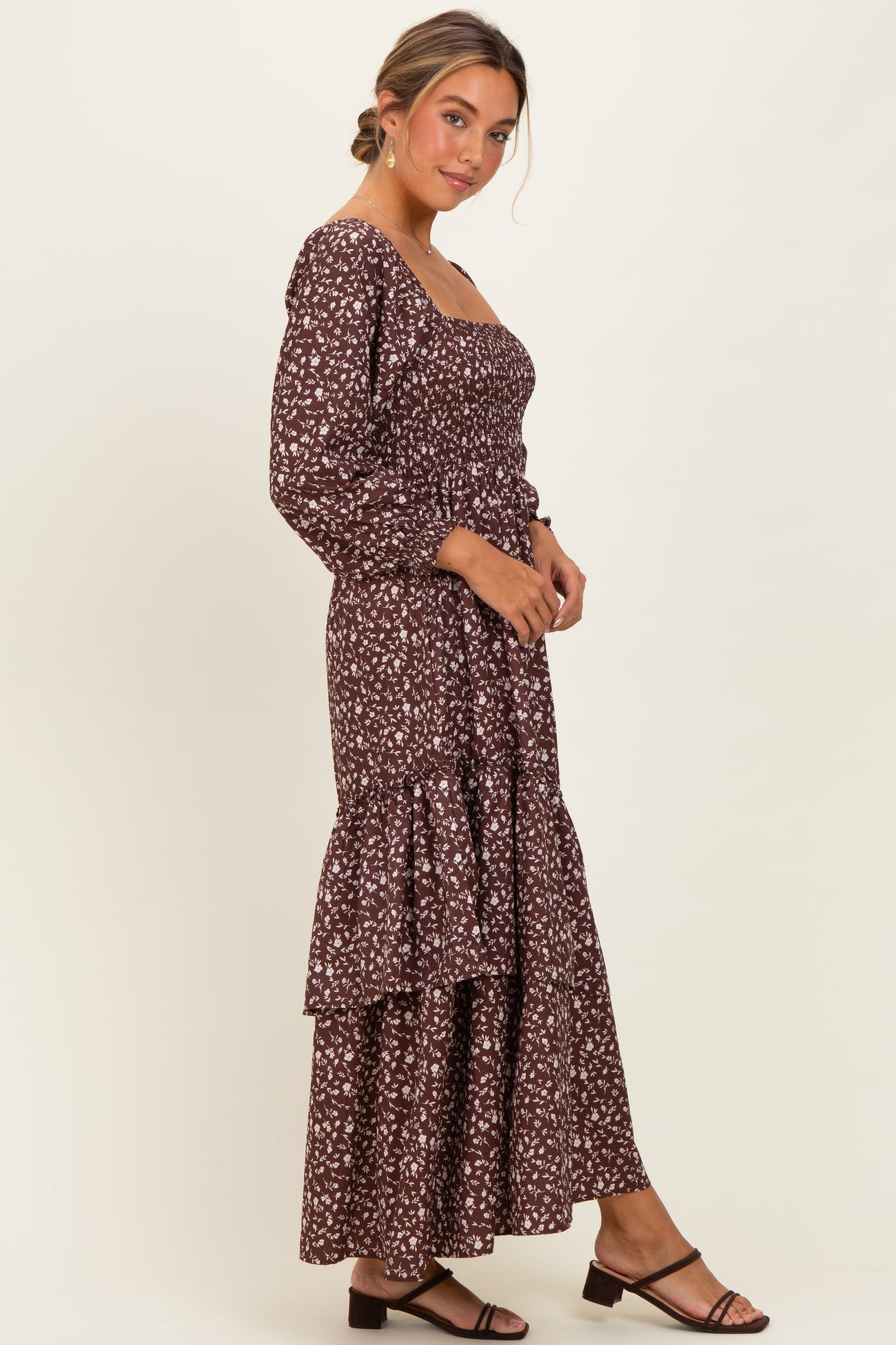 woman wearing a burgundy floral maxi dress with long sleeves and tiered skirt, styled with brown sandals