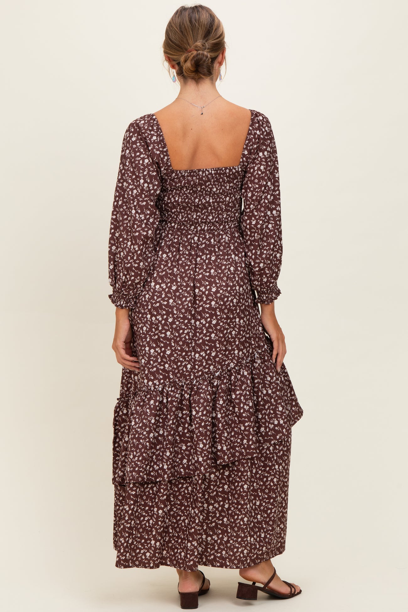 woman wearing a brown floral maxi dress with a smocked bodice and tiered ruffle hem, shown from the back