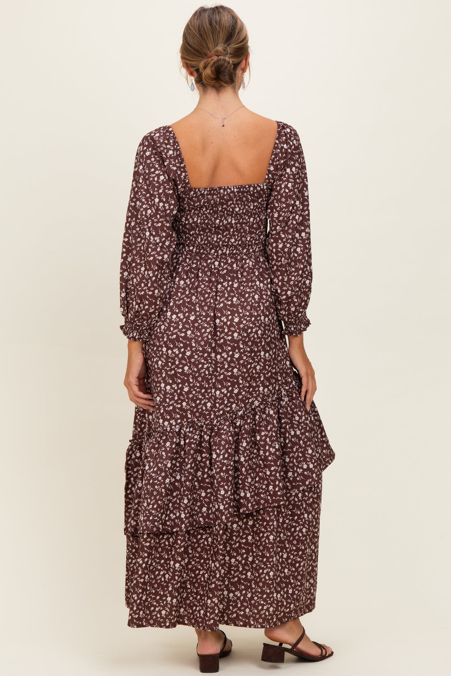 woman wearing a brown floral maxi dress with a smocked bodice and tiered ruffle hem, shown from the back