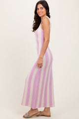 woman wearing a pink and white striped sleeveless maxi dress with a fitted silhouette and side slits, paired with sandals
