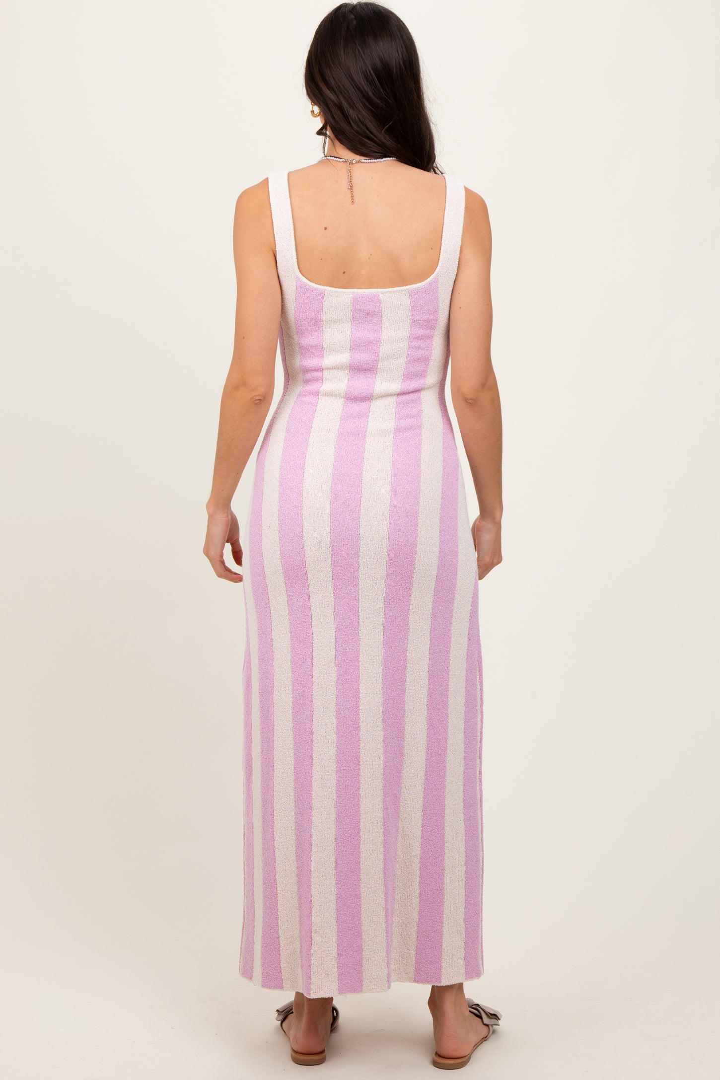 woman wearing a fitted pink and white striped maxi dress, showing the back view