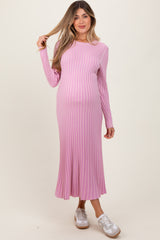 woman wearing a long sleeve light pink ribbed maternity dress with a baby bump visible