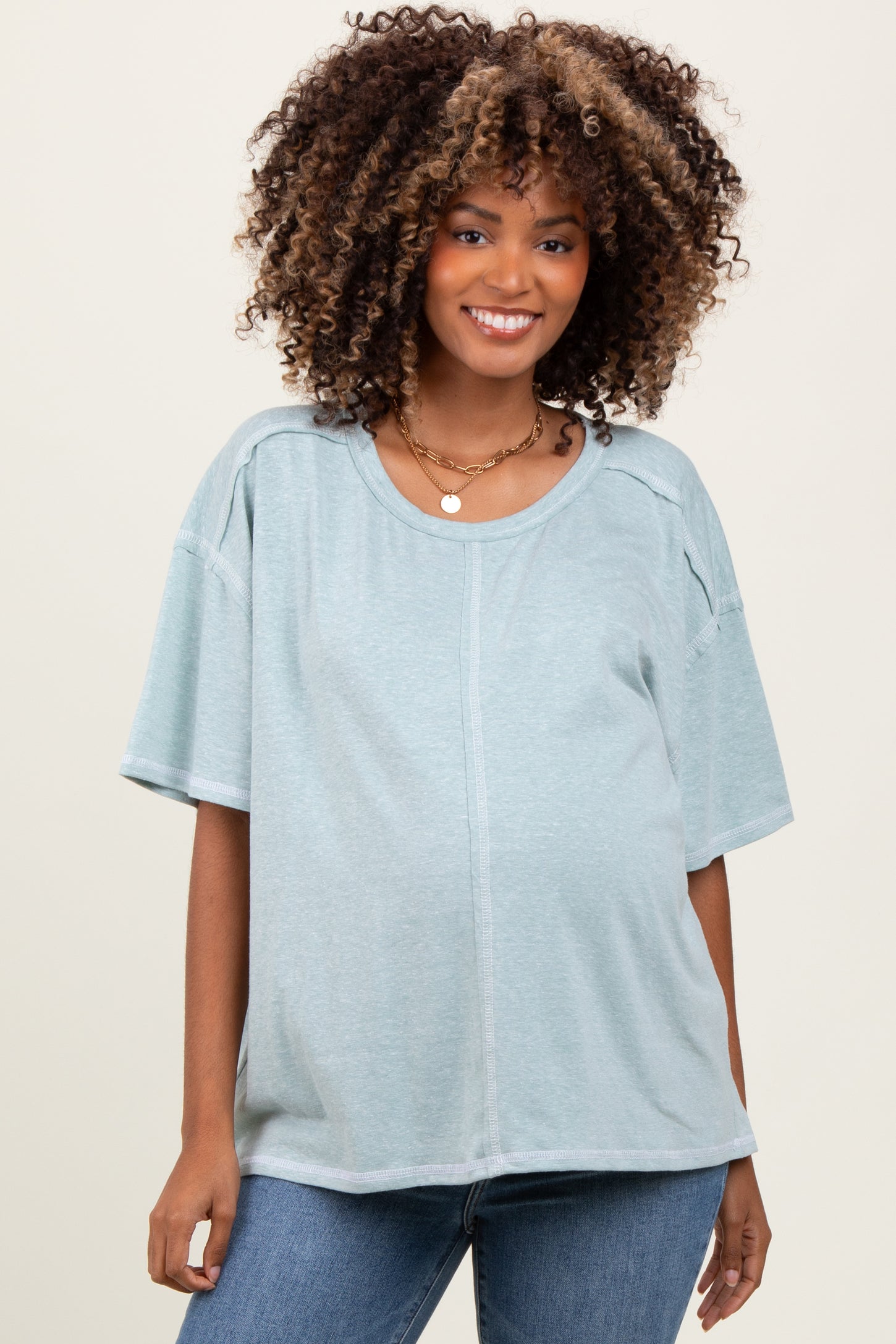 woman wearing a light blue maternity top with short sleeves and a relaxed fit, showing her baby bump