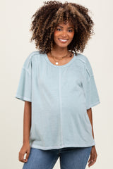 woman wearing a light blue maternity top with short sleeves and a relaxed fit, showing her baby bump