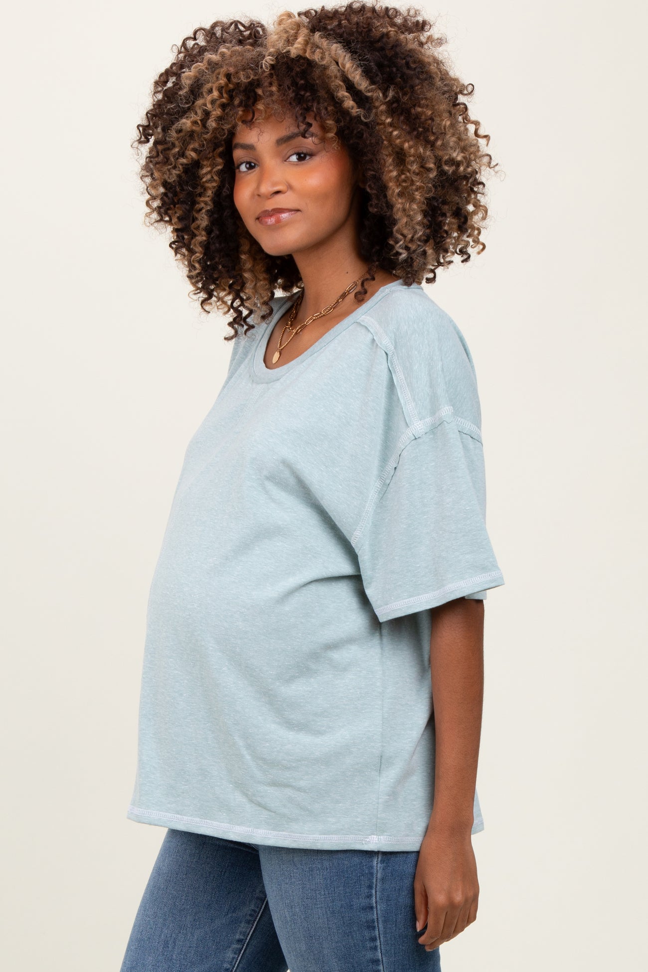 woman wearing a light blue oversized maternity t-shirt and showing her baby bump