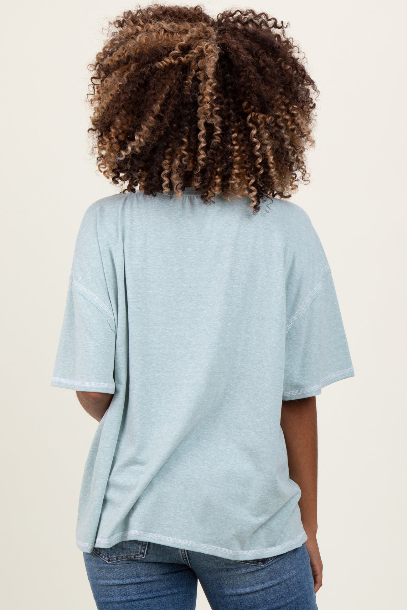 woman wearing a soft green oversized maternity top, showing a relaxed fit from the back