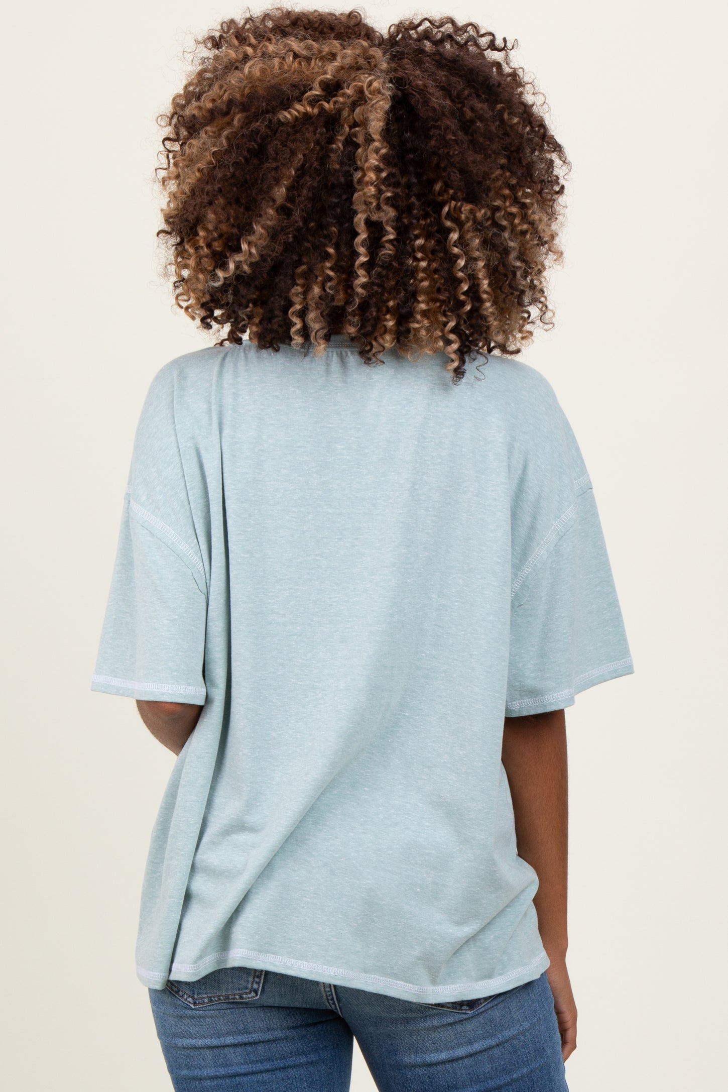 woman wearing a soft green oversized maternity top, showing a relaxed fit from the back