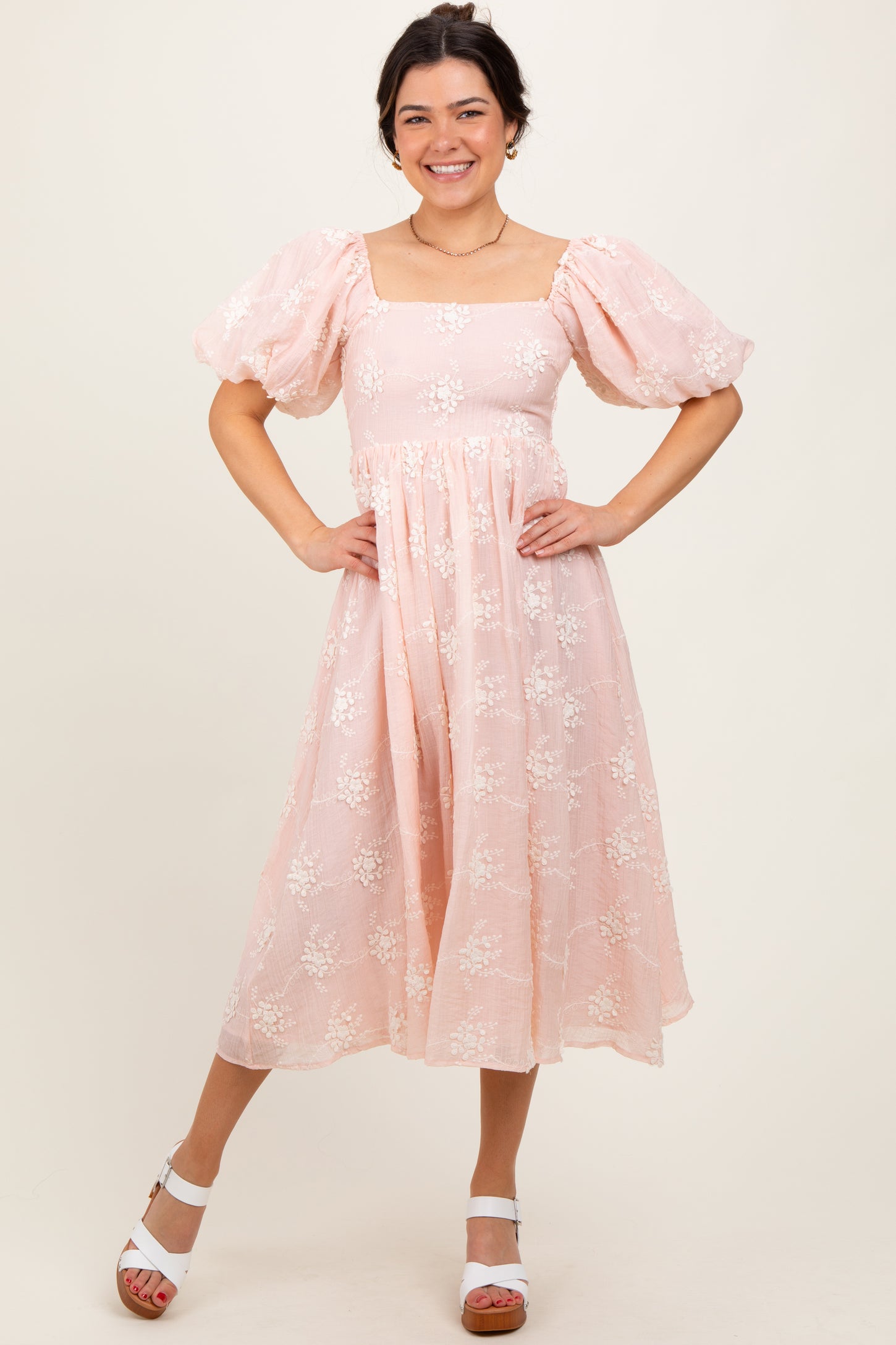 woman wearing a pink floral midi dress with puff sleeves and a square neckline