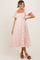 woman wearing a light pink floral maternity dress with puff sleeves and a flowing skirt, showcasing a baby bump