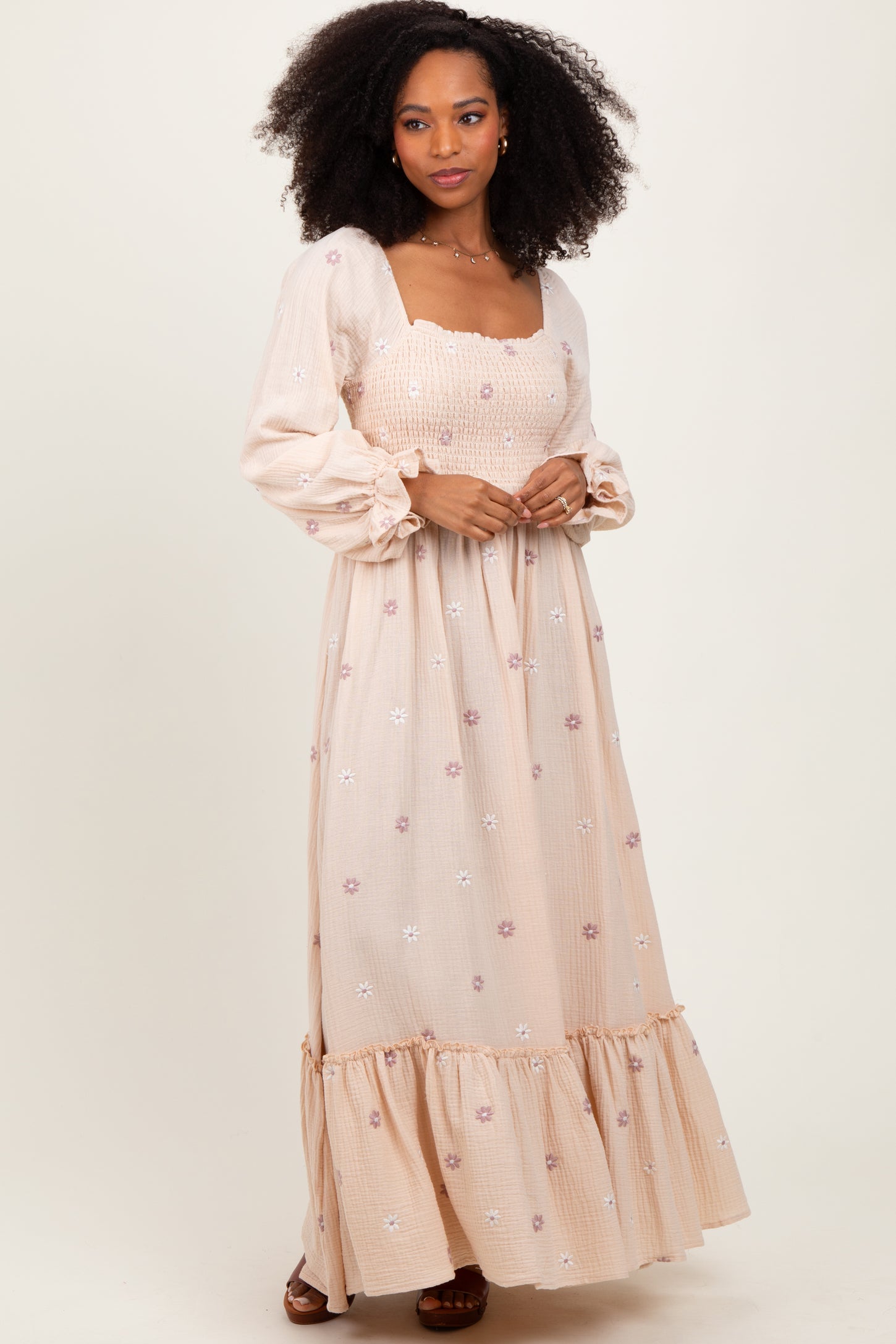 woman wearing a light pink maxi dress with floral embroidery and puff sleeves