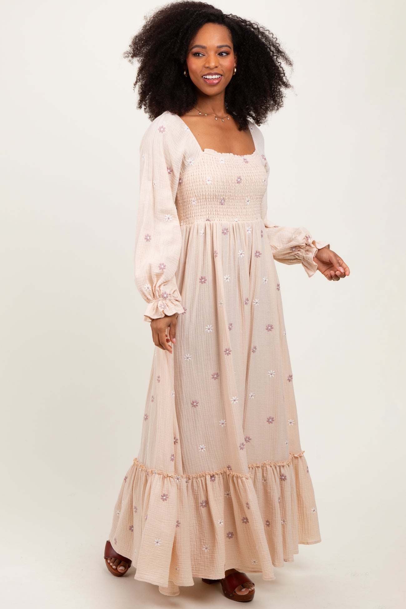 woman wearing a beige long sleeve floral embroidered maxi dress with smocked bodice and ruffle hem