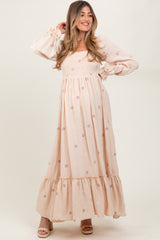 woman wearing a blush pink floral maternity maxi dress with puff sleeves and a smocked bodice, showcasing her baby bump