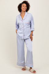 woman wearing a light blue satin pajama set with contrasting pink piping and loose-fitting pants