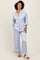 woman wearing a light blue satin pajama set with contrasting pink piping and loose-fitting pants