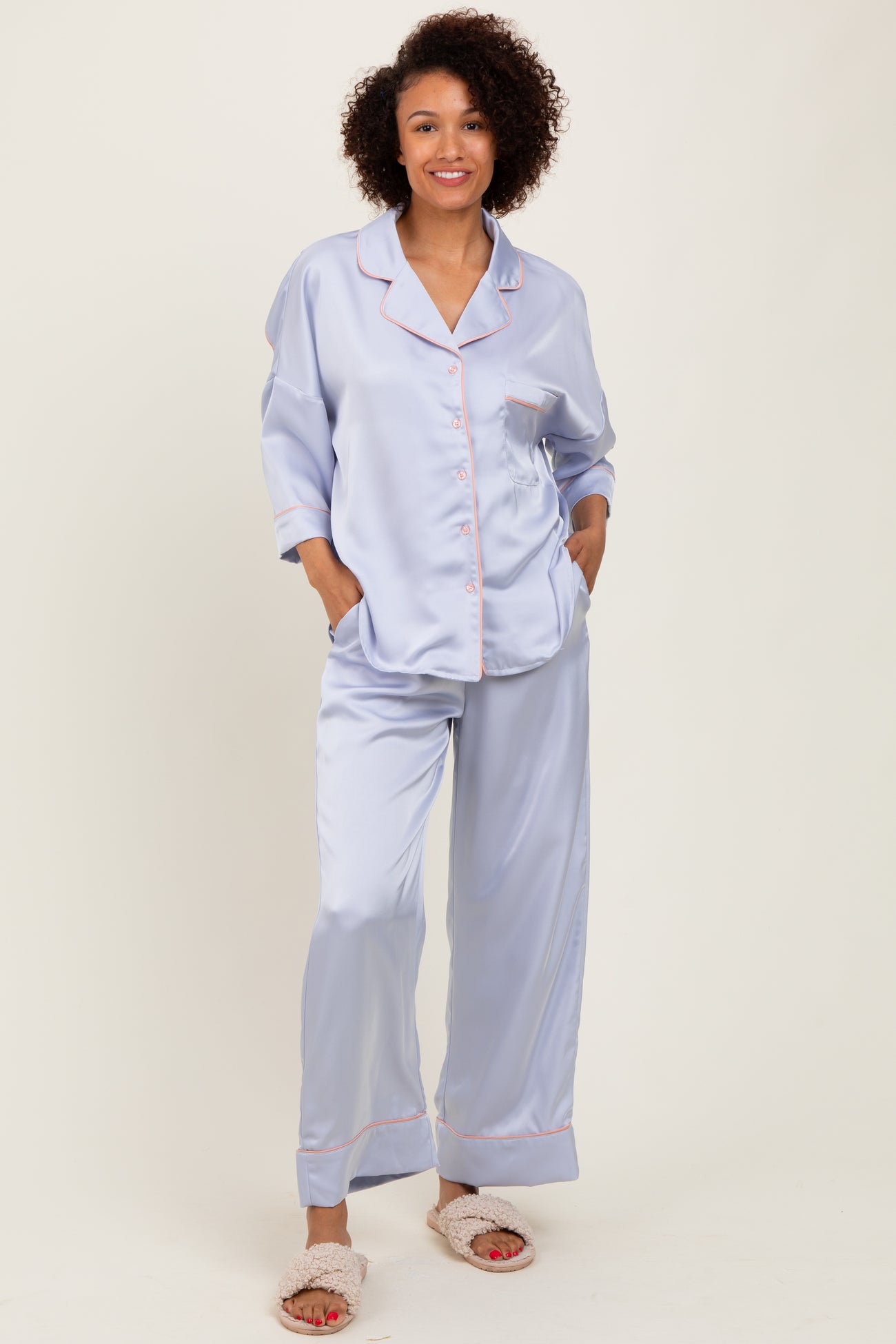 woman wearing a light lavender satin pajama set with contrasting pink piping and pockets