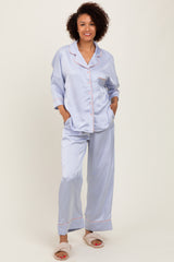 woman wearing a light lavender satin pajama set with contrasting pink piping and pockets