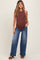 woman wearing a brown ribbed maternity tank top and light blue wide-leg jeans, showing her baby bump