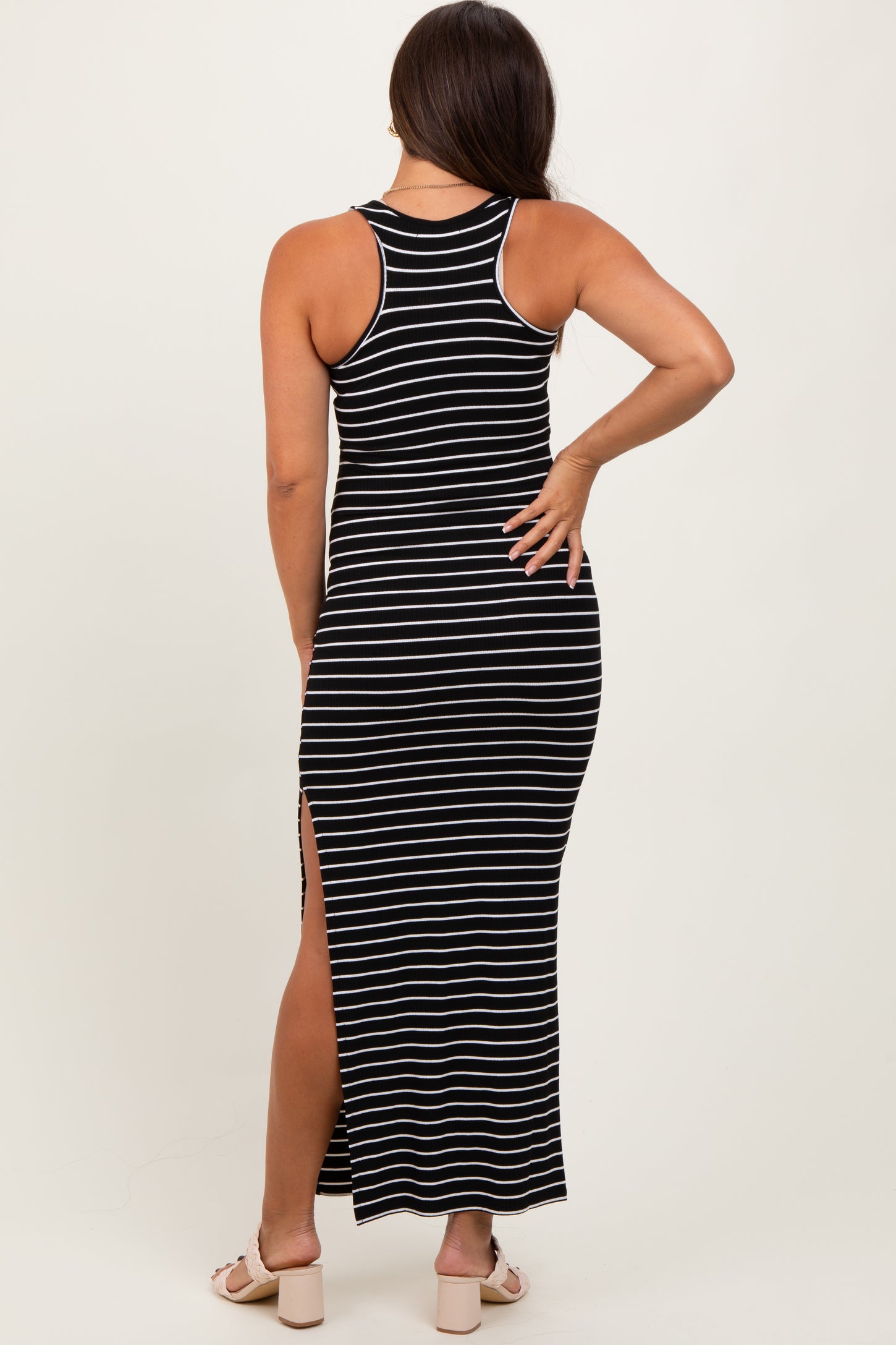 woman wearing a black and white striped maternity maxi dress with a racerback and side slits, showing a baby bump