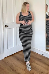 woman wearing a black and white striped maternity maxi dress and holding her baby bump