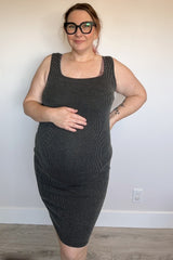 woman wearing a grey ribbed maternity dress and holding her baby bump