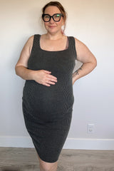 woman wearing a black ribbed maternity dress and holding her baby bump