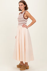 woman wearing a striped sleeveless top with a cream-colored maxi skirt and clogs, posed sideways