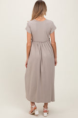 woman wearing a taupe maternity maxi dress with a gathered waist and short sleeves, view from the back