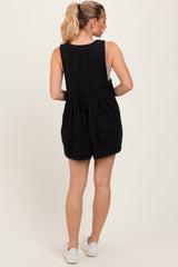 woman wearing a black sleeveless romper showing a pleated back and styled with casual white sneakers