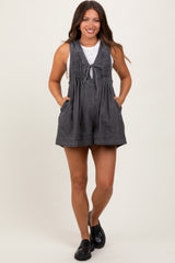woman wearing a charcoal gray maternity romper with a tied front detail and side pockets