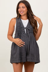 woman wearing a dark grey maternity romper with pleated details and a tie front, showcasing her baby bump