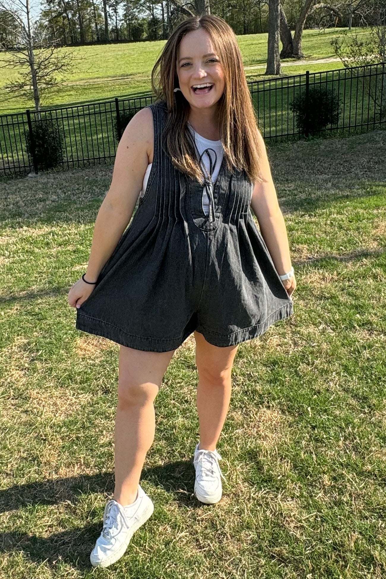 woman wearing a dark gray maternity romper with a loose fit and smiling outdoors, showing a baby bump