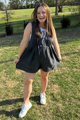 woman wearing a dark gray maternity romper with a loose fit and smiling outdoors, showing a baby bump