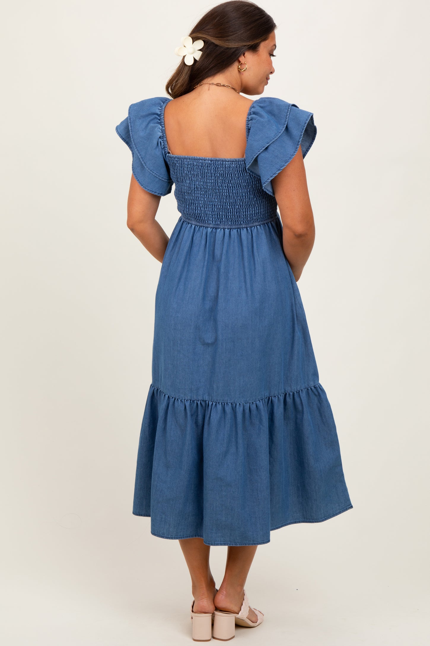 woman wearing a blue maternity dress with ruffled sleeves and a smocked back, featuring a tiered skirt