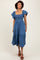 woman wearing a blue chambray midi dress with ruffled sleeves and a tiered skirt