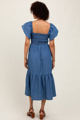 woman wearing a denim blue midi dress with smocked bodice and ruffled sleeves, viewed from the back