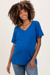 woman wearing a blue v-neck maternity top with a visible baby bump, styled with denim jeans