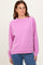woman wearing a pink long sleeve sweater with a relaxed fit and ribbed cuffs, styled over blue jeans